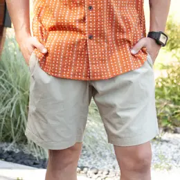 Man standing outside with hands in shorts pockets.
